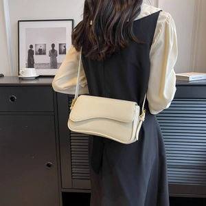 Dettaglio della borsa bianco sporco in pelle martellata con patta ondulata e fibbie d'oro