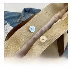 Macro shot of the magnetic snap closure on khaki canvas tote with durable stitching