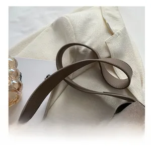 Détail de la bandoulière en cuir grainé marron foncé d'un sac à main seau élégant