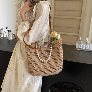 Large straw tote bag with pearl handle and leather straps for beach travel