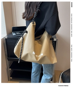 Detail of khaki nylon tote bag featuring a knotted rope strap and white MOTION print