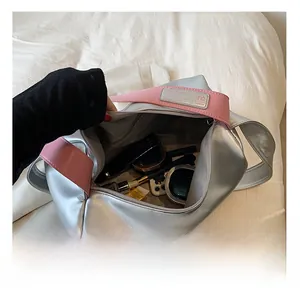 Detail view of the large capacity silver pillow bag showing interior storage and pink strap
