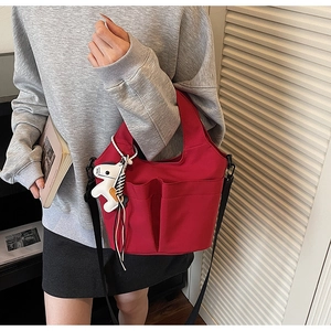 Dettaglio della borsa tote in tela rossa con tracolla e ciondolo a forma di cavallo