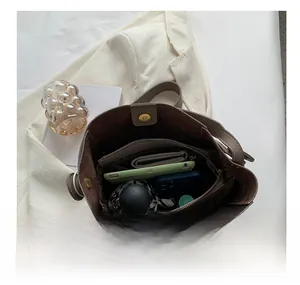 Sac seau en cuir marron montrant un intérieur spacieux avec plusieurs compartiments