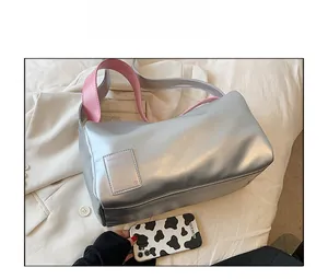 Detailed close-up of a silver metallic cylindrical bag with a vibrant pink shoulder strap