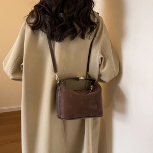 Detail of vintage brown matte PU leather shoulder bag worn with beige trench coat