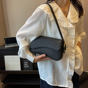 Dettaglio della borsa sottobraccio in pelle nera martellata con fibbia dorata chic