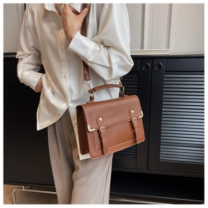 Close-up of a vintage dark brown leather satchel with dual straps and hand handle