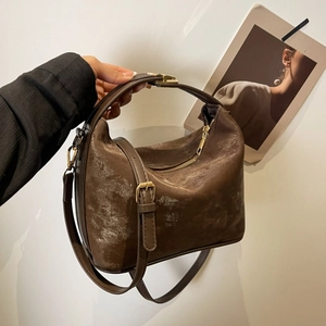 Detail of vintage brown PU leather handbag with adjustable strap and golden zipper hardware