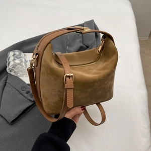 Close-up of brown suede shoulder bag with gold hardware and textured finish