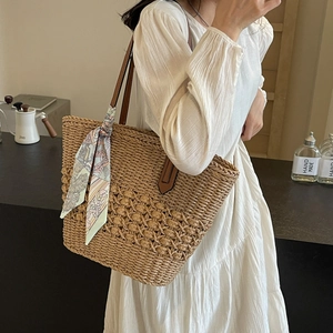 Handmade woven straw tote bag with floral silk scarf and leather handles for beach vacation