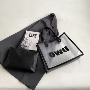Large PVC transparent tote bag with black leather inner pouch on grey suit background