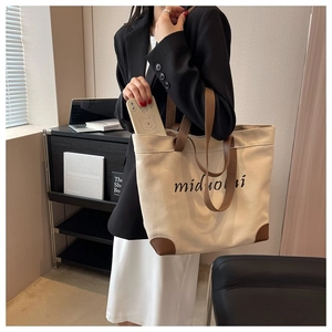 Detailed view of canvas tote bag with leather handles and reinforced corner patches
