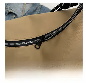 Detailed close-up of smooth black zipper and khaky nylon fabric on women's tote bag