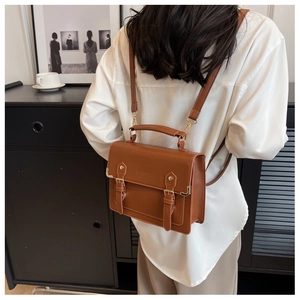 Rear view of a model wearing the brown vintage leather backpack with twin buckle straps