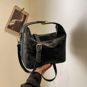 Close-up of a black textured PU leather handbag with gold hardware and top handle