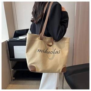 Detailed view of beige canvas tote bag with brown leather handles and brand logo