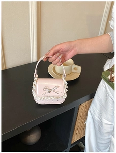 Close-up of pink mini lace handbag with silver bow and heart cutout details