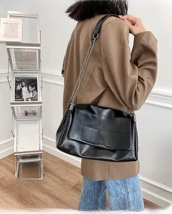Détail d'un sac à bandoulière en cuir matelassé noir avec chaîne métallique élégante