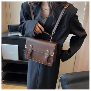 Detail of vintage dark brown handbag with golden buckle and adjustable strap