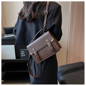Classic vintage brown leather briefcase bag shown crossbody on a model in an office setting