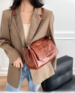 Détail d'un sac à bandoulière matelassé marron caramel avec chaîne porté par un mannequin