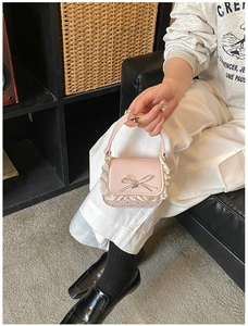 Detail of pink mini handbag with 3D bow and delicate white lace trim on shiny leather