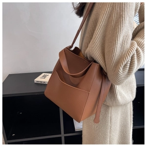 Vue détaillée du sac seau en cuir grainé marron avec large bandoulière sur tenue beige