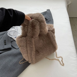 Détail d'un sac seau en peluche marron avec chaîne dorée et texture en fausse fourrure