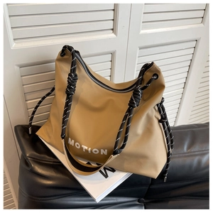 Close-up of khaki nylon tote bag with MOTION lettering and striped rope strap