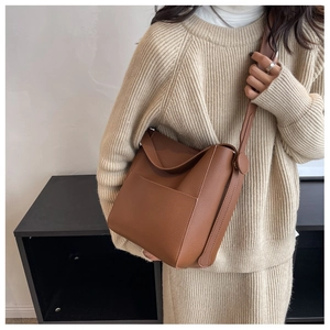 Détail du sac seau bandoulière en cuir grainé marron foncé avec poche frontale et bandoulière