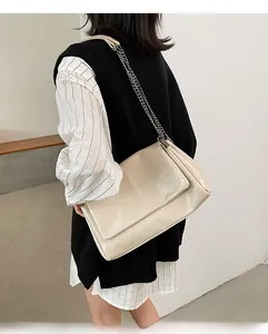Détail d'un sac à bandoulière en cuir verni beige matelassé avec chaîne en métal