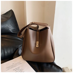 Detail view of brown pebbled leather bucket bag with golden buckle and vertical strap