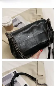 Détail de la texture en cuir noir à motif carré et bandoulière en chaîne métal