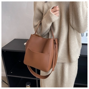 Détail du sac seau en cuir grainé marron caramel avec poche porté par un mannequin