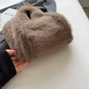 Gros plan du sac seau marron en fausse fourrure pelucheuse avec chaîne dorée