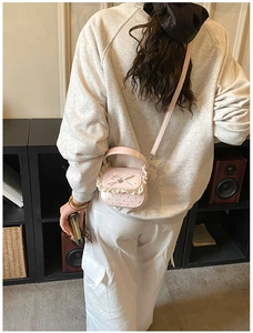 Pink mini crossbody bag featuring sweet lace trim and bow accent shown on a model
