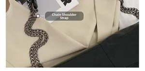 Détail de la bandoulière chaîne sur un sac à main en cuir noir et tissu plissé beige
