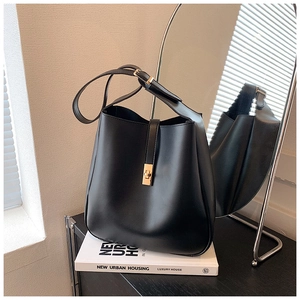 Detail of minimalist black leather bucket bag with elegant golden square twist lock buckle