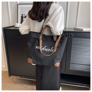 Detail view of canvas tote bag with leather handles and white miduold lettering
