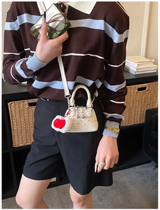 Polka dot shell bag with red heart plush charm shown in a cozy lifestyle setting