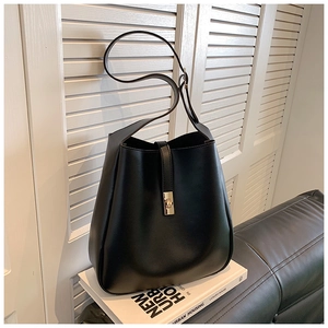 Detail of black leather bucket bag showing refined texture and golden metal buckle closure