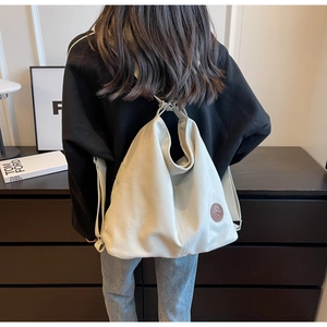 Detailed back view of a minimalist cream canvas backpack with a round leather logo patch