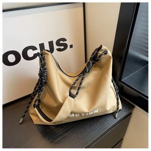 Detail of khaki nylon tote bag featuring thick braided rope strap and MOTION text print