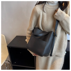Vue détaillée du sac seau noir en cuir grainé avec large bandoulière réglable et poche
