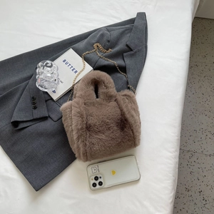 Sac seau en fausse fourrure marron avec chaîne dorée sur une veste de costume grise