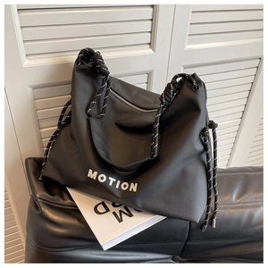 Detailed macro view of black nylon tote bag featuring a bicolor braided rope handle