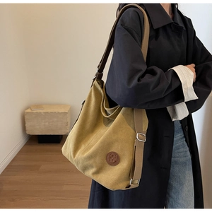 Detail of mustard yellow canvas hobo bag showing texture and circular leather logo patch