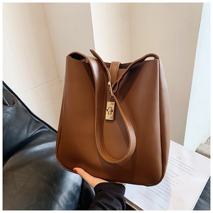 Detail view of large dark brown bucket bag with shiny texture and metal lock buckle