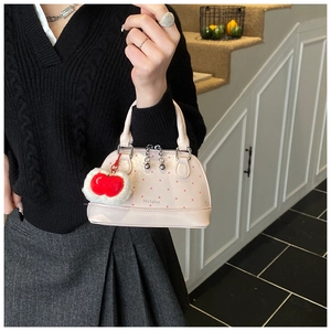 Detail of pink polka dot mini handbag with plush apple charm and chic metal chain decoration